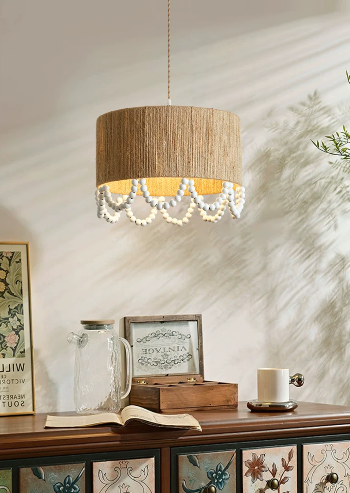Dappled sunlight falls across this Clérachic pendant, lit above a wood sideboard styled with jars and books.