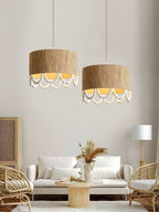 Two of this Clérachic pendant hang lit above rattan lounge chairs and a vase of dried pampas grass.