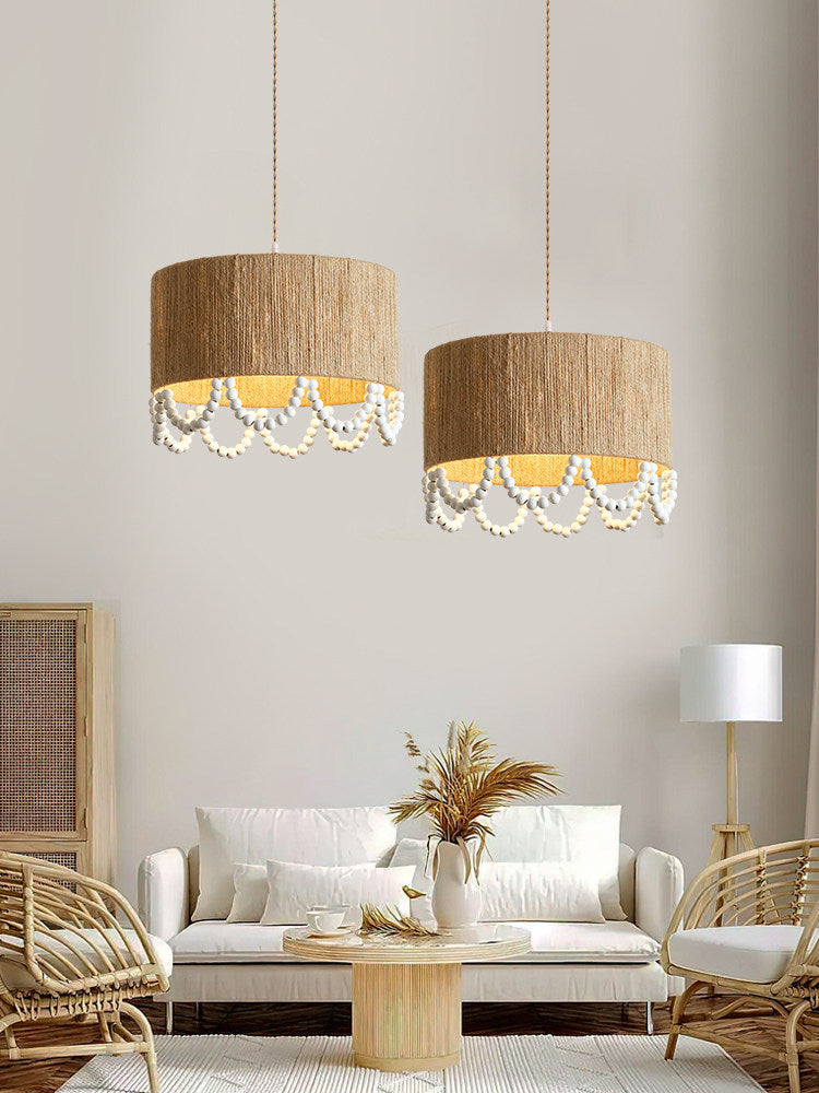 Two of this Clérachic pendant hang lit above rattan lounge chairs and a vase of dried pampas grass.