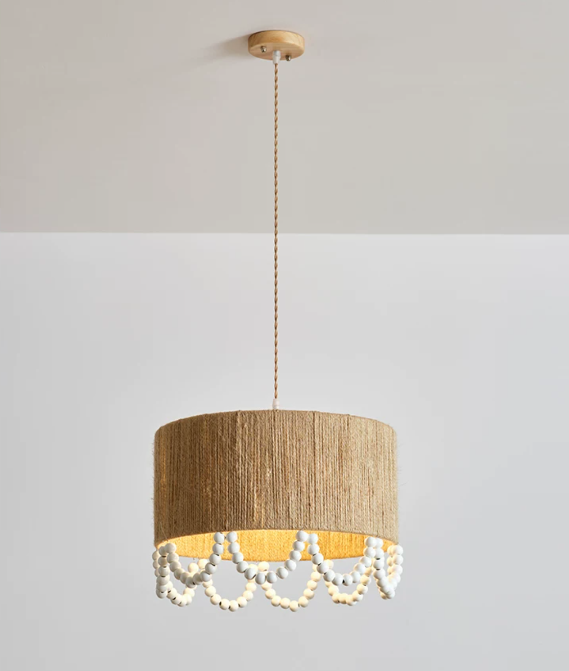 Ceiling-mount view of this Clérachic pendant, its rope shade glowing warm against a plain grey backdrop.