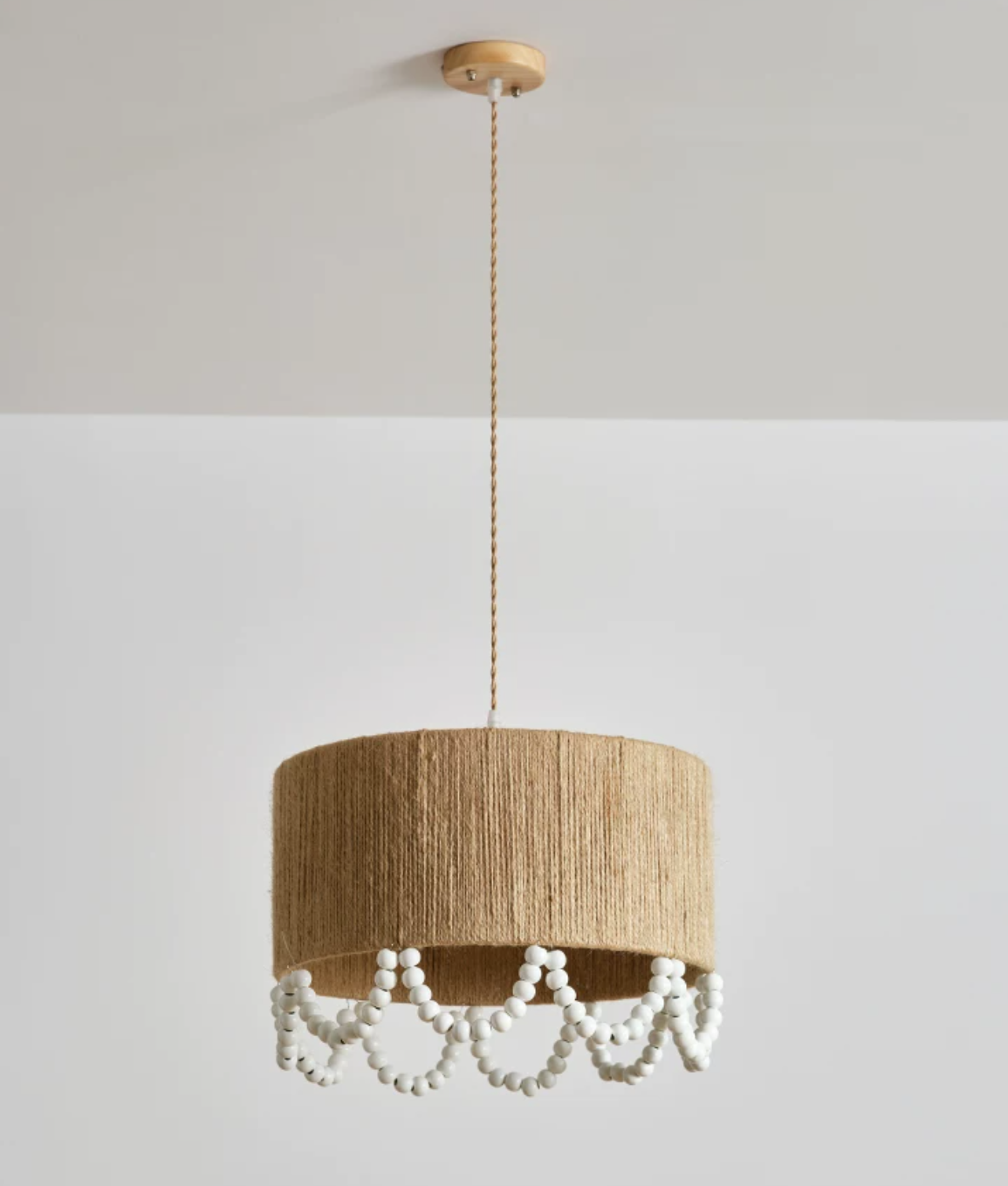 Full-drop studio shot of this Clérachic pendant, the beaded fringe swaying beneath a lit hemp rope shade.