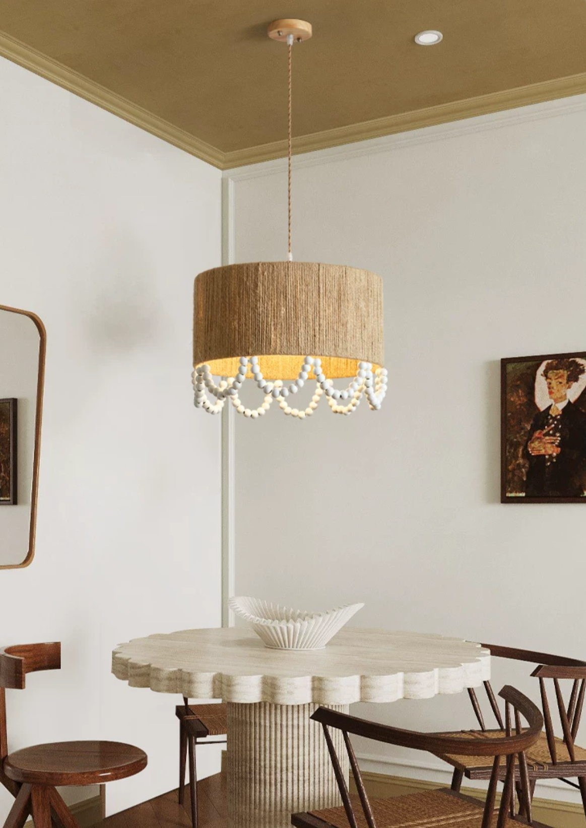 Above a round pedestal dining table beneath a gold-toned ceiling, this Clérachic pendant glows near a wall mirror.