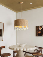 This Clérachic pendant lights a dining corner with a round pedestal table, a framed portrait, and a gold-toned ceiling above.