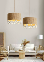 Two of this Clérachic pendant glow above a boucle sofa and a rattan armchair in a plain-walled room.