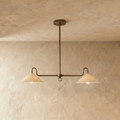 Clérachic pendant light in vintage brass with two cone shades, hung from a single rod against a plaster ceiling.