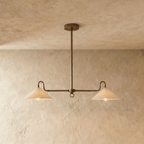 Clérachic pendant light in vintage brass with two cone shades, hung from a single rod against a plaster ceiling.