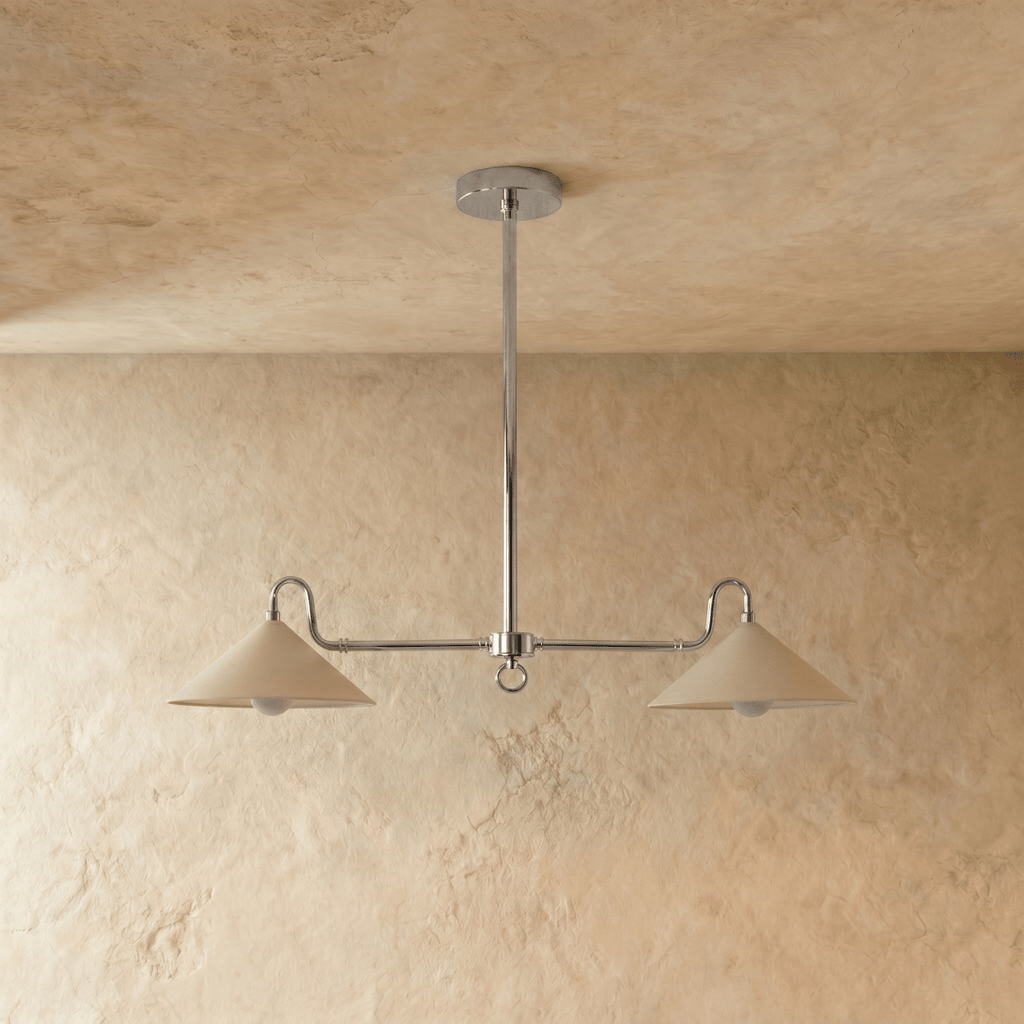 This chrome Clérachic pendant light is shown at a slight angle, both cone shades glowing warmly.