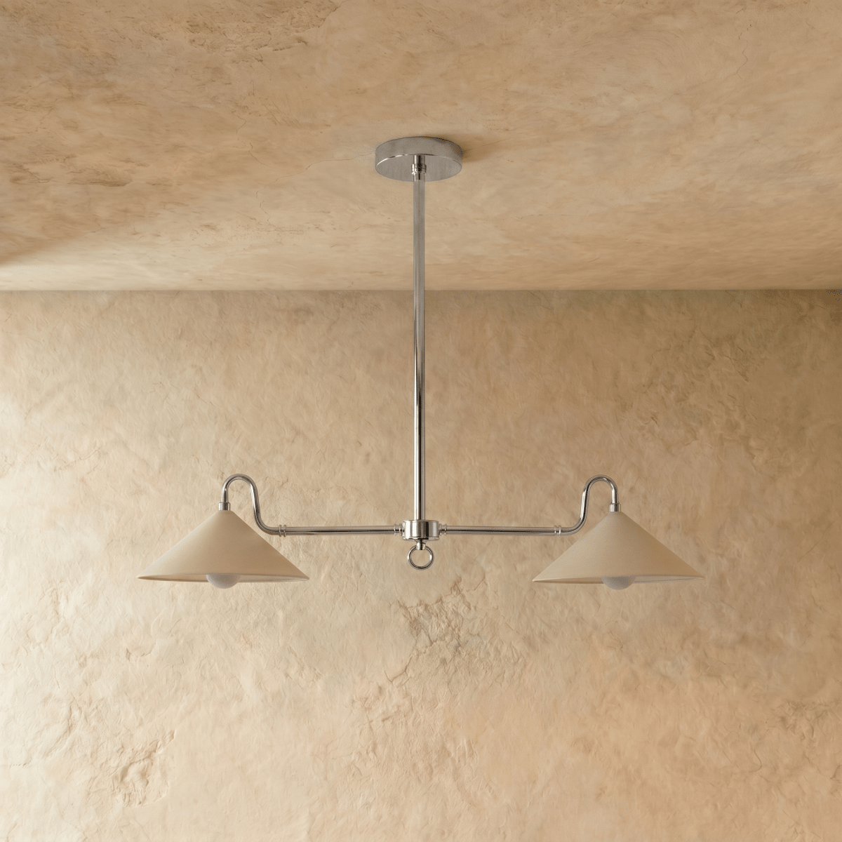 This chrome Clérachic pendant light is shown at a slight angle, both cone shades glowing warmly.