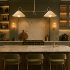 A chrome Clérachic pendant light lights a marble kitchen island beneath green cabinetry and shelving.