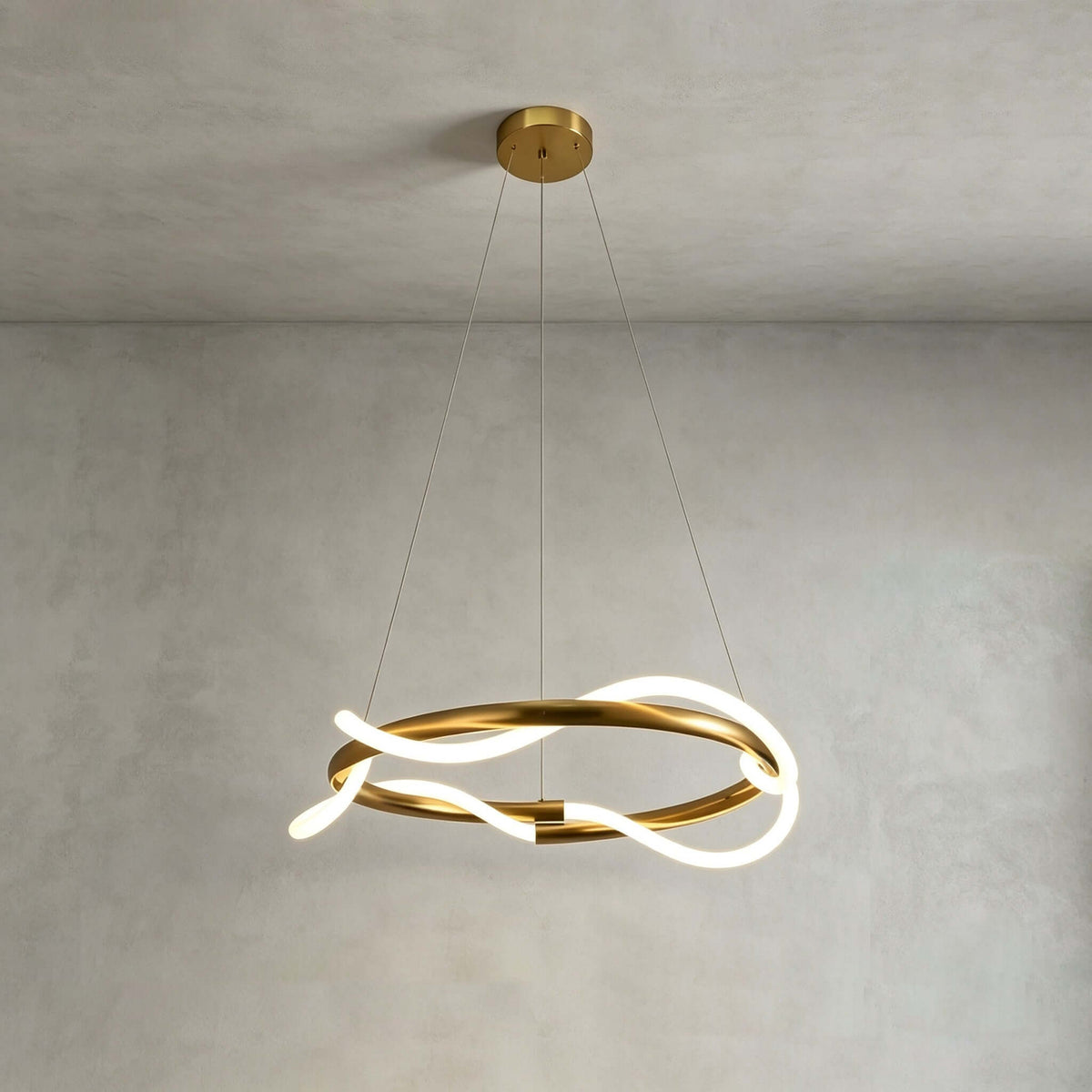 A round Clérachic wave pendant lit against a grey plaster wall, with a brass canopy and two fine suspension wires.