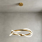 Clérachic pendant seen from slightly below, its silicone ribbon glowing as it twists around a brass ring on a grey plaster wall.
