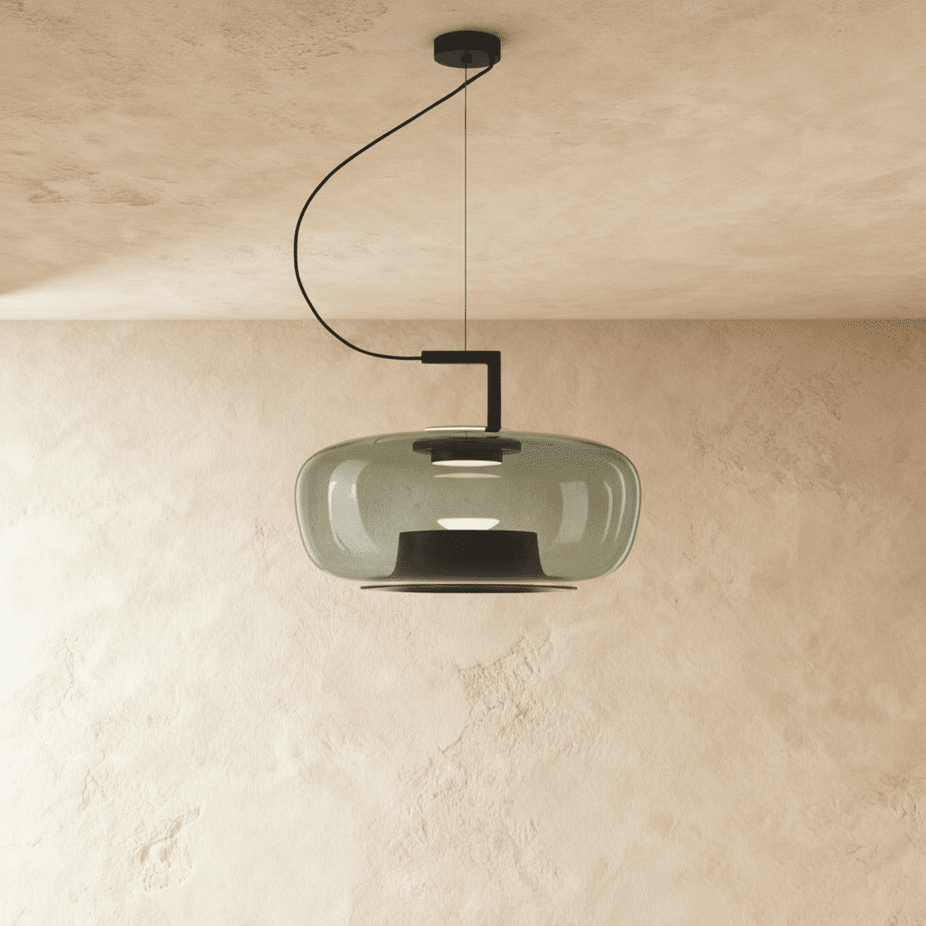 Clérachic glass pendant in smoky grey, wide rounded shade on a black curved arm and cord, over a limewash plaster wall.