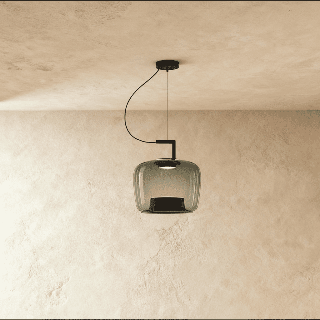 Clérachic mid-size pendant in smoky grey glass, a softly squared shade hung from a black arm, lit over limewash plaster.