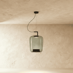 Clérachic tall pendant in green-tinted glass, an elongated shade with a black base cone, lit on a black arm.