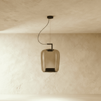 Clérachic tall amber glass pendant, unlit, with a black inner cone, hanging from a black arm and cord.
