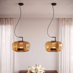 Clérachic pair of amber glass pendants lit warmly beside sheer curtains, with white lilies below.