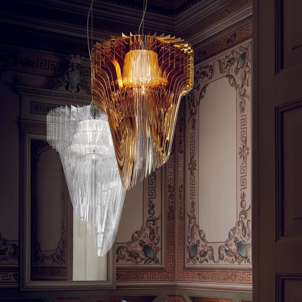 A copper-gold and a clear fringe pendant from Clérachic hang together in the corner of a room with painted panelled walls.