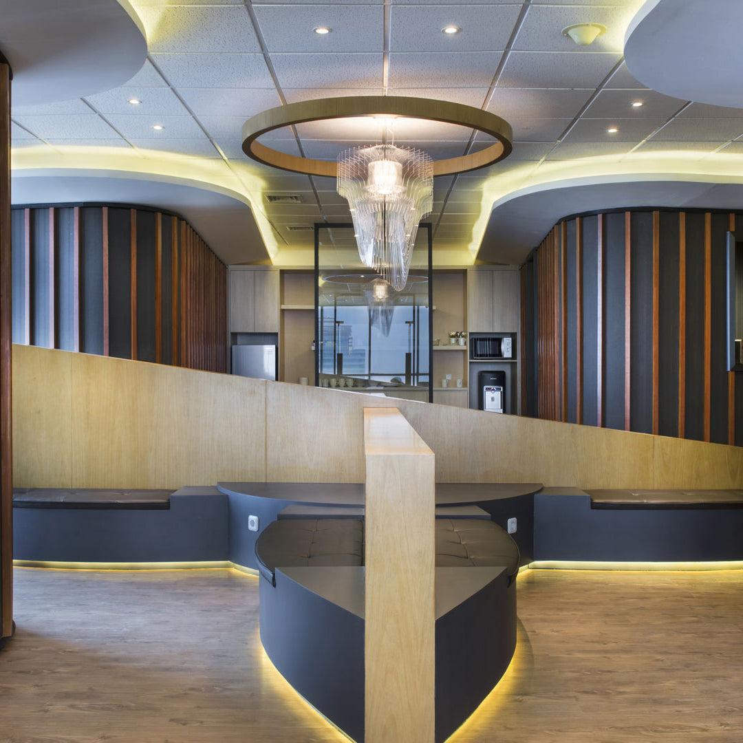 A clear fringe pendant from Clérachic hangs inside a ring of warm light in a wide, curved-ceiling lobby with a timber desk.