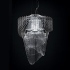A clear fringe pendant from Clérachic seen against a black backdrop, its fins and inner shade glowing white.