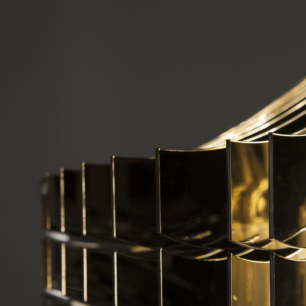 Close view of the polished gold fins stacked in a ring on a Clérachic fringe pendant, each curved plate catching the light.