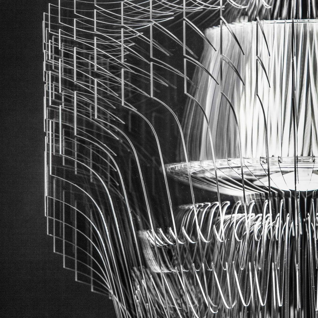 Close view of clear acrylic fins and the inner shade of a Clérachic fringe pendant, in black and white against a dark ground.