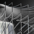 Close view of thin clear acrylic fins fanning out in curves on a Clérachic pendant, with soft light behind them.