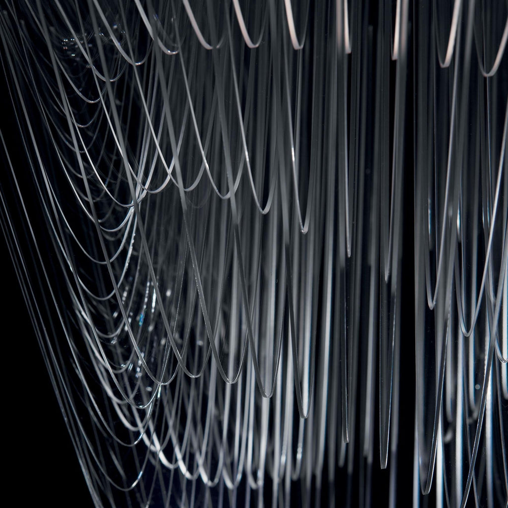 Close view of clear acrylic fins hanging in long, fine curves on a Clérachic pendant, shown against a dark backdrop.
