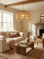 Beneath an exposed wood beam, this Clérachic pendant lights a living room with a linen sofa and stone fireplace.