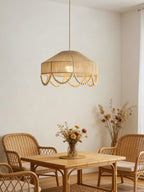 Over a small rattan breakfast table set with dried flowers, this Clérachic pendant glows in a plain white nook.