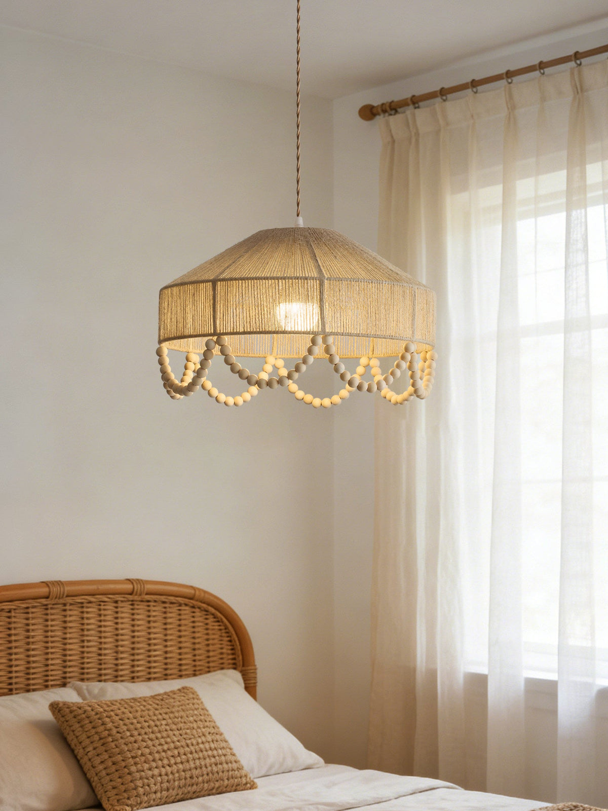 Close beside a rattan headboard and sheer curtains, this Clérachic pendant glows above the bed.