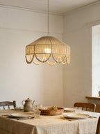 Above a linen-set dining table with pottery and glassware, this Clérachic pendant glows warm.