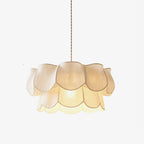 Close view of this Clérachic pendant's linen petals, stacked in two tiers around a glowing centre, on a plain backdrop.