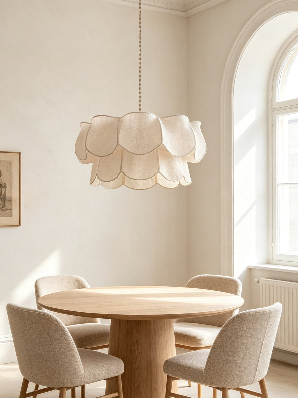 This Clérachic pendant hangs above a round wood table with beige upholstered chairs, beneath an arched window.