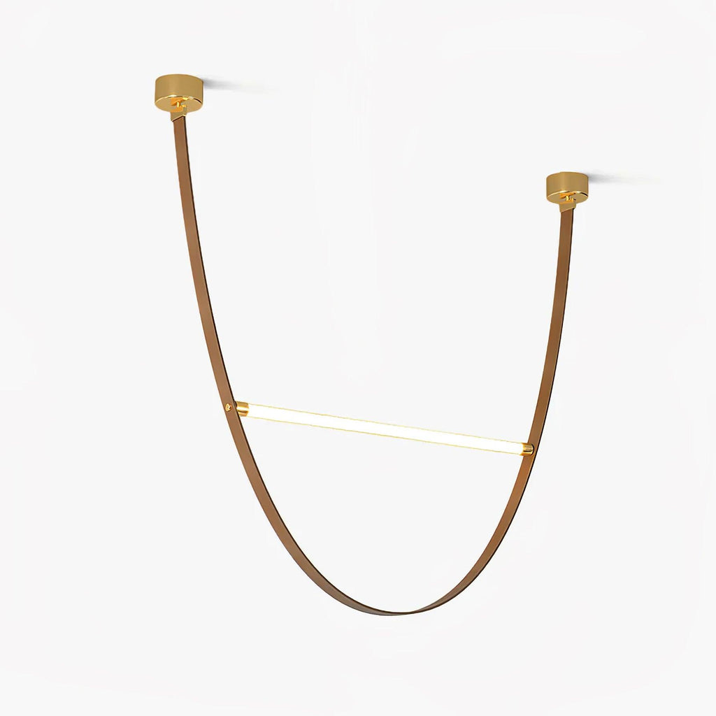 Two brass canopy plates and a single curved leather strap loop holding one glowing LED bar, on this Clérachic pendant against a white backdrop.