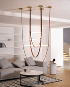 Six brass canopy plates on the ceiling feed this Clérachic pendant's leather loops down towards a sofa and a round coffee table.