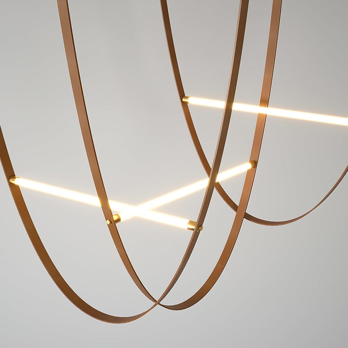 Looped tan leather straps cross two lit bars, shown close up on a plain grey ceiling and wall on this Clérachic pendant.