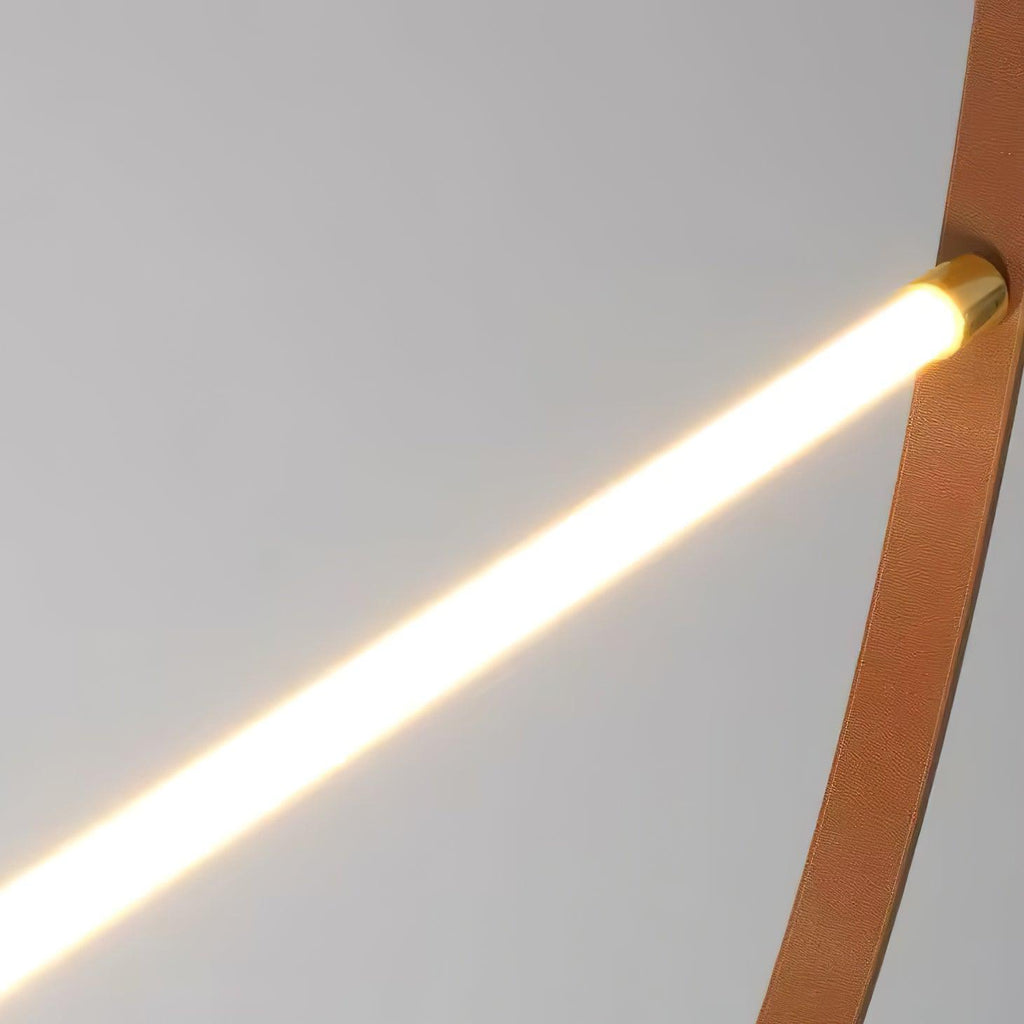 Close view of a lit LED bar ending in a brass cap where it meets the leather strap on this Clérachic pendant.