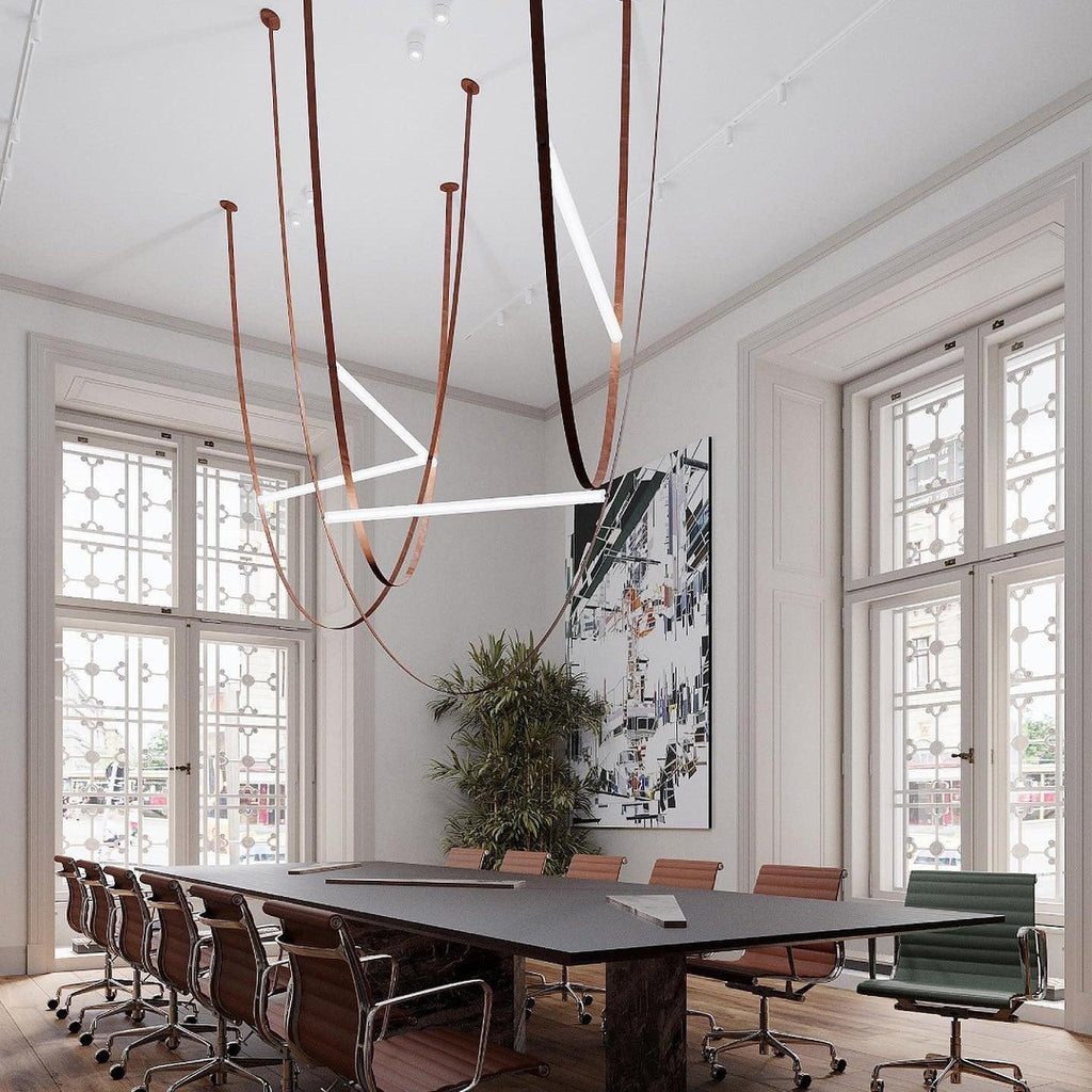 Light bars at several angles on leather loops, a Clérachic pendant hung in a tall meeting room above a long dark table.