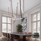 Light bars at several angles on leather loops, a Clérachic pendant hung in a tall meeting room above a long dark table.