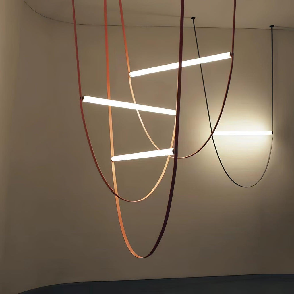 Three bright bars on copper-toned leather loops, with a black loop beside them, on this Clérachic pendant against a dark wall.
