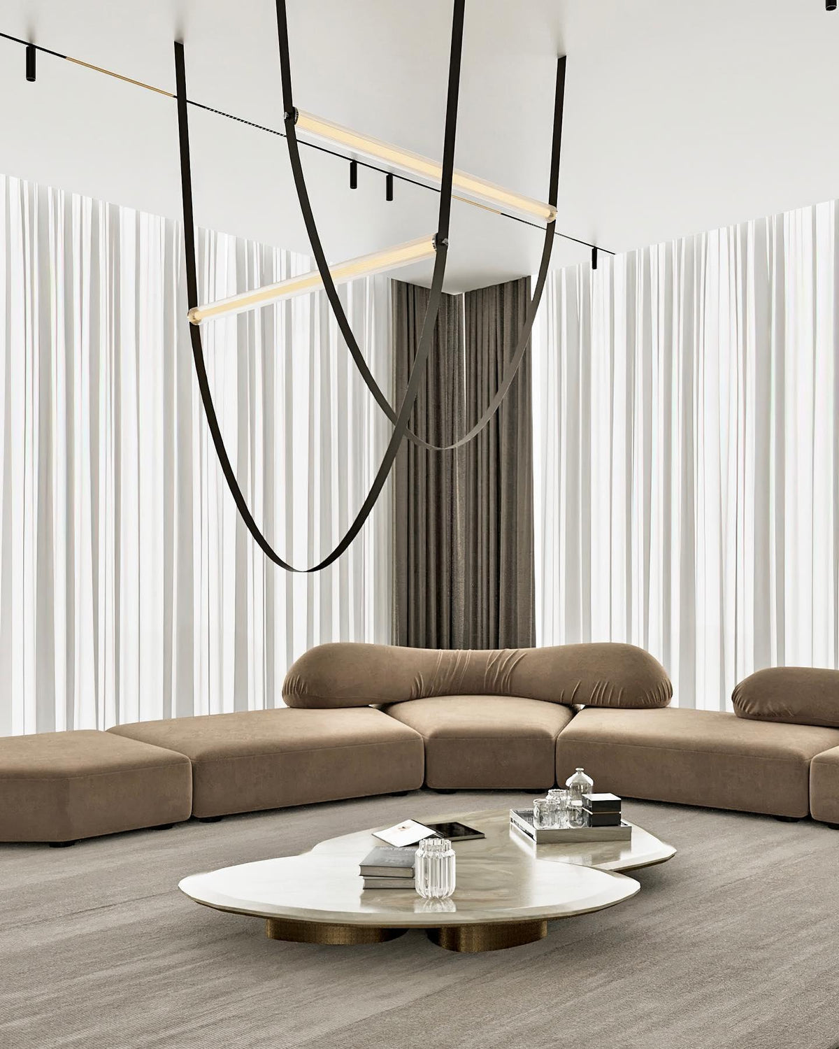 A black leather loop with a lit bar hangs in front of white curtains above a sand-coloured sofa and oval coffee table, on this Clérachic pendant.