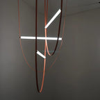 Three lit bars at different angles on leather loops, this Clérachic pendant seen against a dark grey wall.