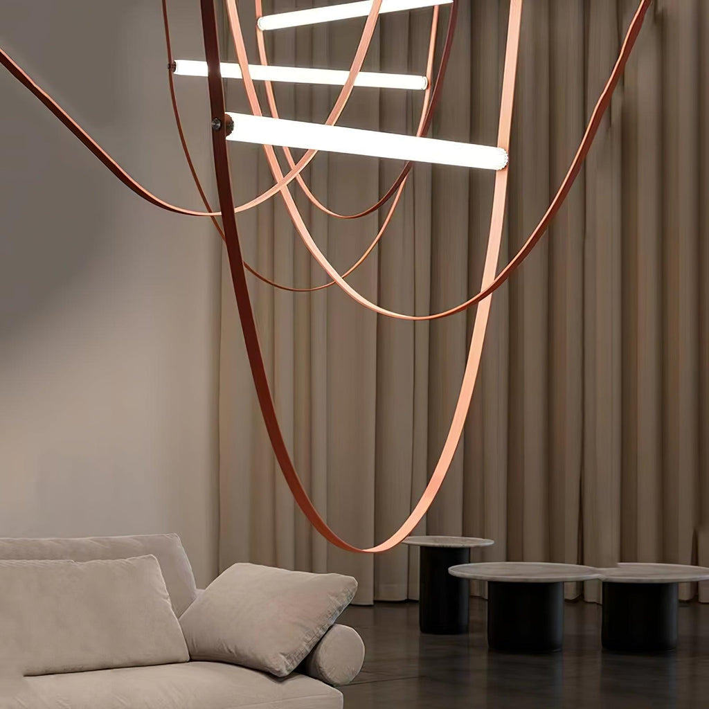Underneath view of this Clérachic pendant, with long leather loops sweeping past cream curtains above a sofa and dark side tables.