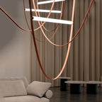 Underneath view of this Clérachic pendant, with long leather loops sweeping past cream curtains above a sofa and dark side tables.