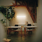 A single wide bar glows on a thin leather loop of this Clérachic pendant in a loft office with timber beams and a rope swing.