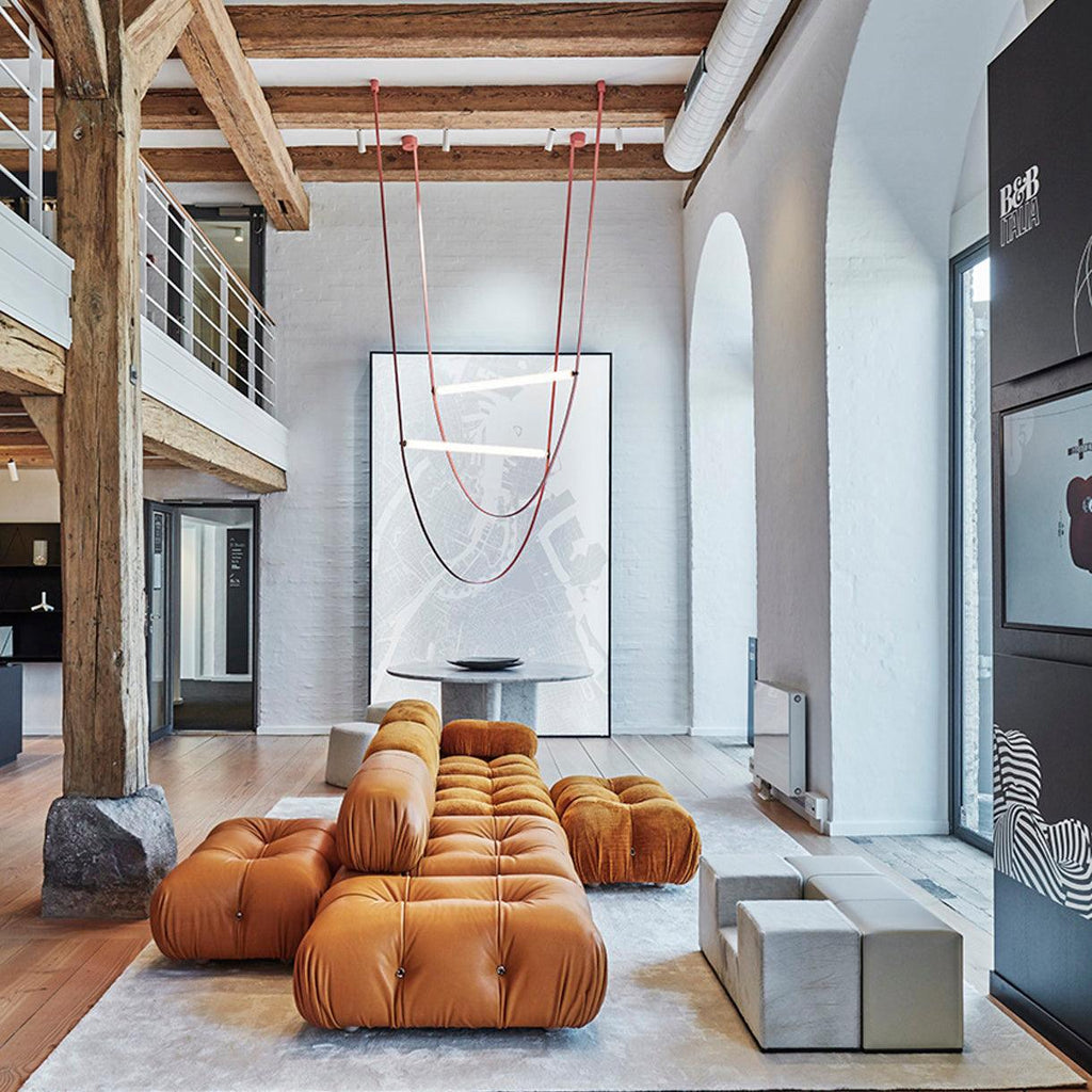 This Clérachic pendant hangs very high in a double-height space with exposed timber beams, above a tan leather modular sofa.