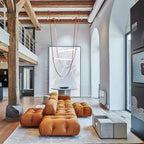 This Clérachic pendant hangs very high in a double-height space with exposed timber beams, above a tan leather modular sofa.