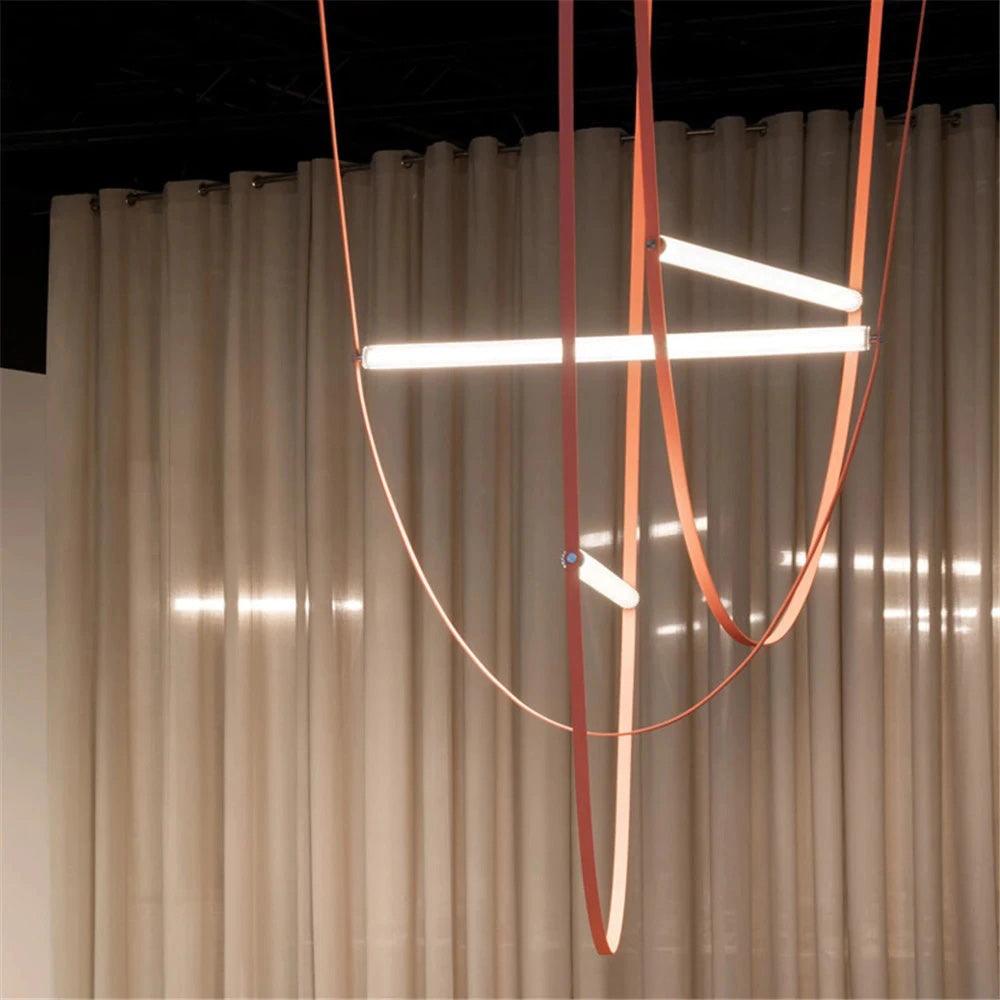 Three bright bars on copper-toned leather loops, this Clérachic pendant in front of long, softly gathered curtains.