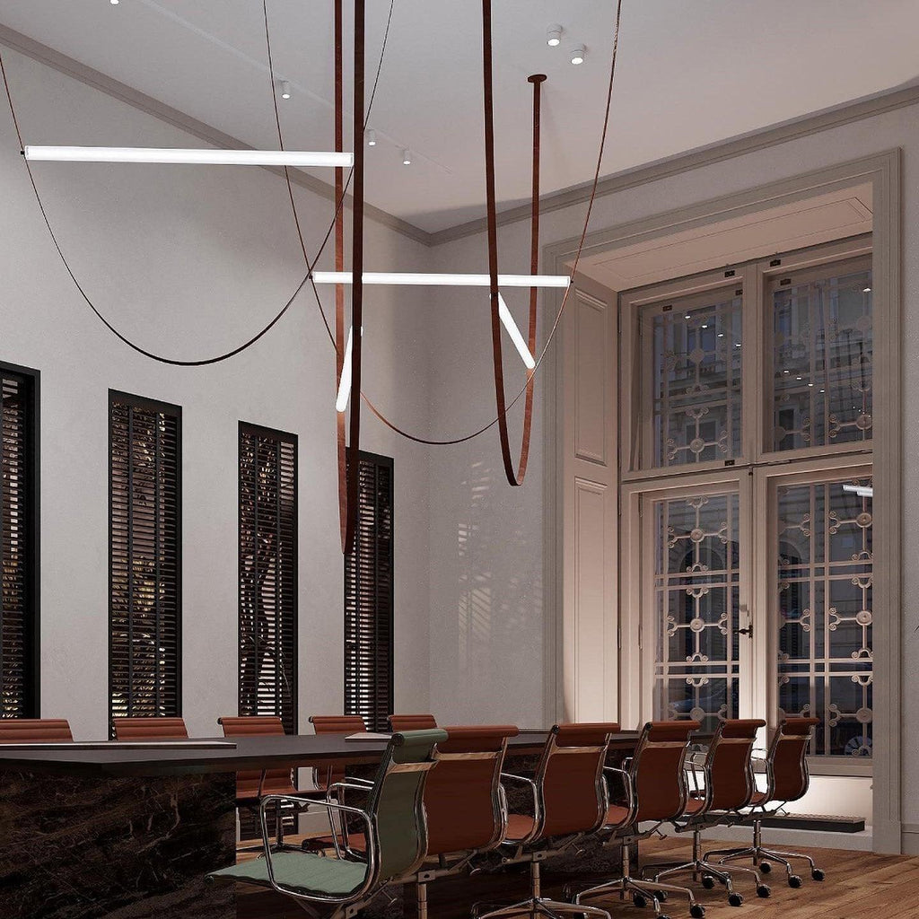 Several bars and leather loops from this Clérachic pendant hang in a high-ceilinged room with dark shutters and a long table.
