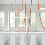 Light bars and tan leather loops from this Clérachic pendant in a white room with tall windows and a polished stone floor.